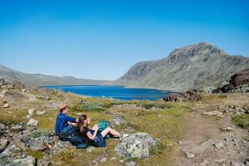 two hikers resting on Besseggen ridge over Gjende lake in Jotunheimen National Park, Norway
