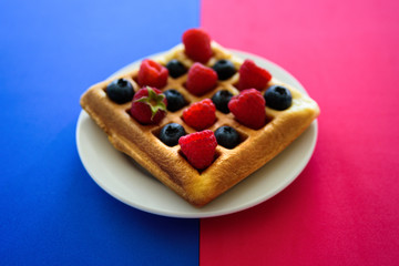 Belgian waffles with berries on colorful background