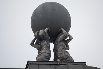 Statue in the form of women holding a ball on the roof of the building. Kiev, Ukraine