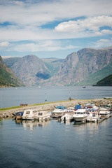 Fototapeta na wymiar boats moored in calm harbour and majestic mountain landscape, Aurlandsfjord, Flam (Aurlandsfjorden), Norway