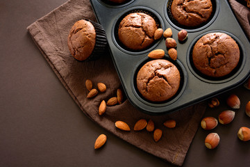 Homemade chocolate muffins (brownies) with cinnamon, almonds and hazelnuts on brown paper background