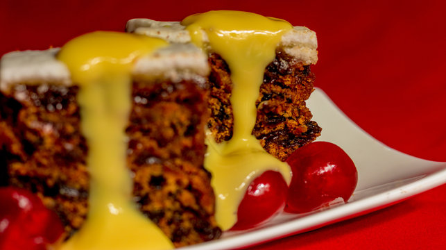 Fruitcake with pouring custard on red background