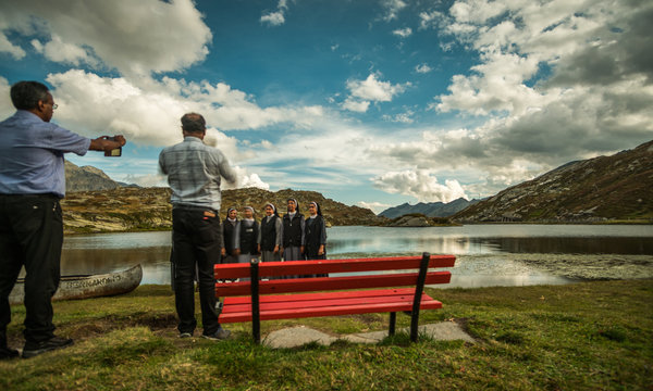 priest take a picture of nuns in a beautiful place in the alps with a lake