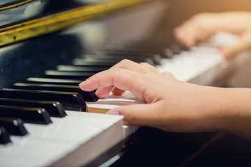 Fototapeta premium Selective focus to fingers of woman teaching boy to play the piano.