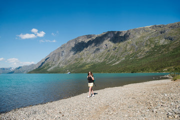 beautiful young woman with backpack walking near Gjende lake, Besseggen ridge, Jotunheimen National Park, Norway
