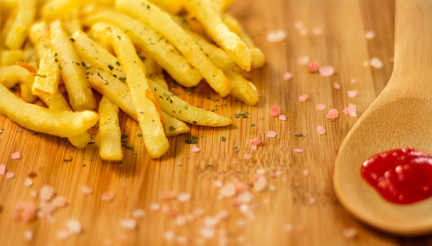 Potato fries plated on wooden board with ketchup (selective focus on fries)