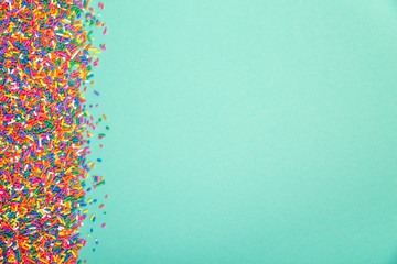 Colorful sprinkles on edge of green background