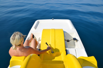 Woman on a pedal boat on water level in sunny day. Summer vacation by the sea.