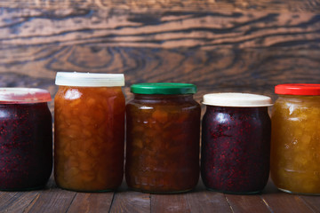 Jars with jam on a brown wooden background