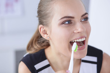 Smiling young woman with healthy teeth brushing her teeth