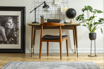 Mid-century modern chair with leather seat by a desk with an industrial lamp and a retro typewriter...