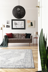 Low angle view of an artistic living room interior with a large, black, spherical pendant light...