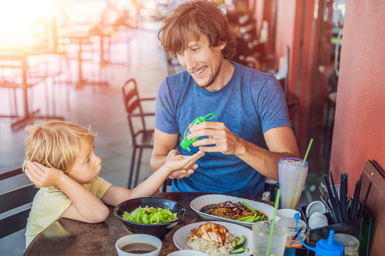 Father and son using wash hand sanitizer gel before eating in a cafe with sunlight