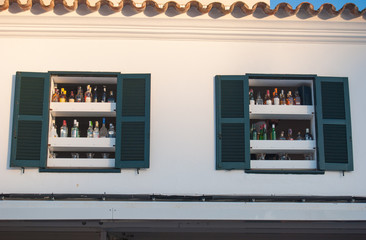 Two open windows with a lot of bottles of spirits