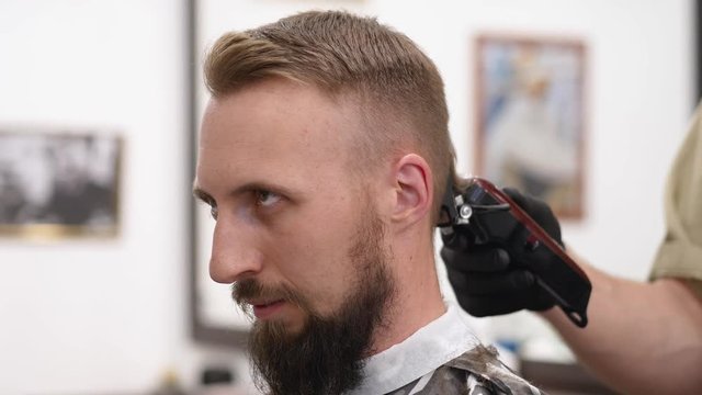 The hairdresser tips the client's head and shaves the neck area