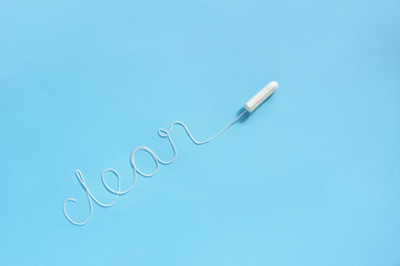 Word CLEAN from white thread hygienic female tampon is located diagonally on blue background. Concept hygiene and health women and adolescents during menstrual cycle. Flat Lay, copy space