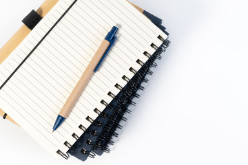Stack of book, office mathematics education class with spiral bound notebook, wooden pen and copy space. Blank notebook paper lines for text.