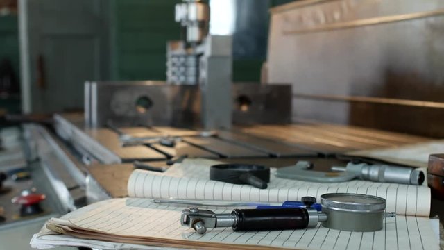 A private workshop for working with metal parts, in the background a drilling machine drills a hole in the pulley, on the table lie measuring instruments, industry