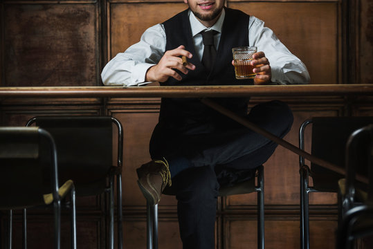 Man sits in the luxury bar in male gentlemen club and drinks alcohol