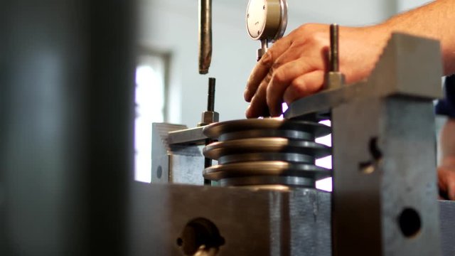 The male specialist measures the size of the tolerance device and the value in the metal pulley for manufacturing, close-up, measuring