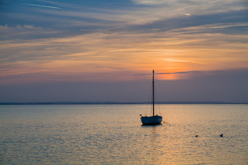 Lonely boat moored in the bay. Sunset.