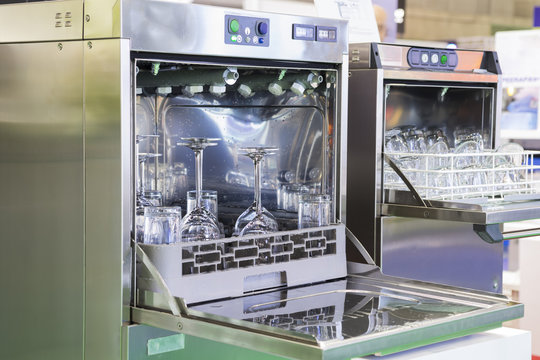 Open door of dishwasher with clean glasses by using water; food industrial equipment background