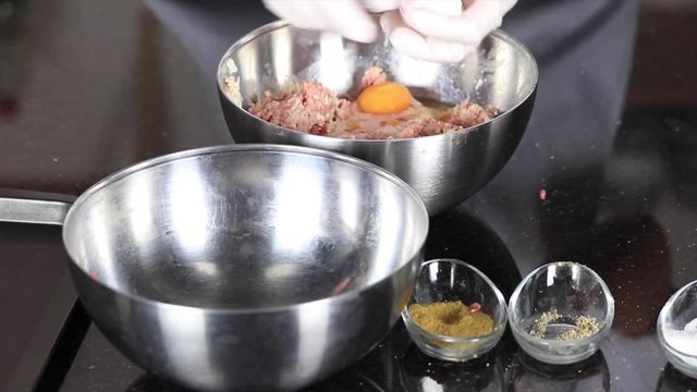 chef is preparing meatball with mince, egg and bread
