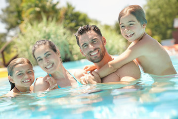Fototapeta premium Portrait of happy family at the swimming-pool in summer