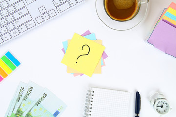 Multicolored stickers note with question mark on white desktop next to a mug of coffee and keyboard.