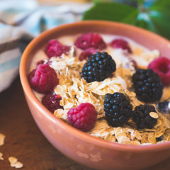Smoothie yogurt bowl with oats and berries on wooden rustic board. Healthy eating breakfast