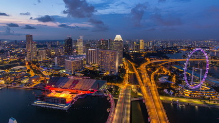 Fototapeta na wymiar Skyline of Singapore with famous Singapore Ferries Wheel day to night timelapse at twilight