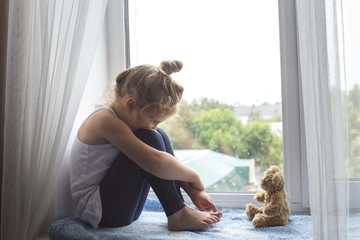 Girl sitting on the windowsill, it's raining