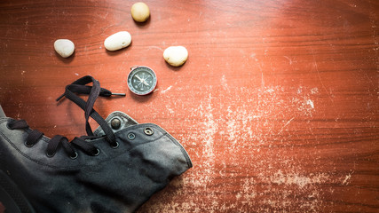 Touristic magnetic compass and boots on wooden table