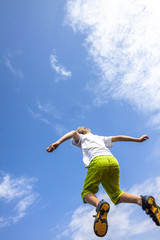 happiness, childhood, freedom, movement and people concept - happy boy jumping in air into the blue sky