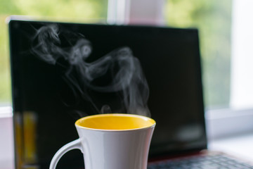 A cup of hot coffee on a laptop background.