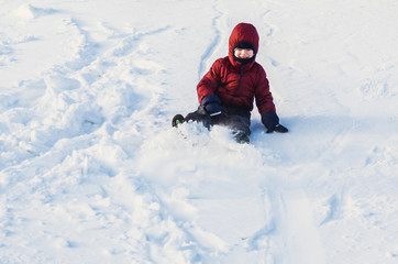 Fototapeta na wymiar Boy riding down the slope of a snowy hill