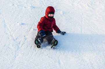 Fototapeta na wymiar Boy riding down the slope of a snowy hill