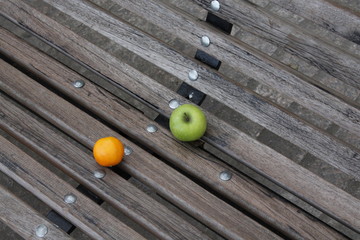 orange and apple on a bench