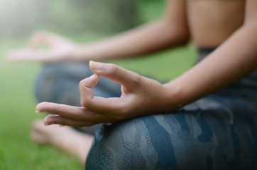 Close up at the hands of the woman is sitting yoga in the park