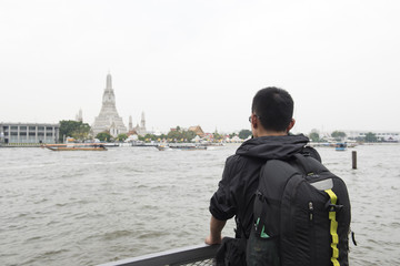 Young asian man look Bangkok temple and Chao Phra ya river.