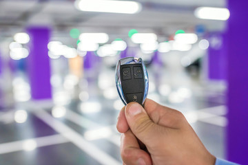 Car Keys. Male hand holding car key, on a parking background