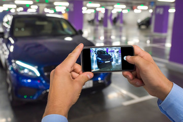 Phone in the man's hands against the background of the car.