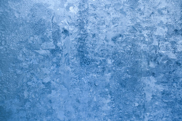 Natural blue winter frosty icy pattern on window pane. 