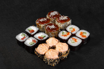 Set of sushi, rolls, uramaki, hosomaki, tempura, with teriyaki, lava sauce, raw seafood, soy sauce, marinated ginger and wasabi, black isolated background Side view For the menu, restaurant, bar cafe