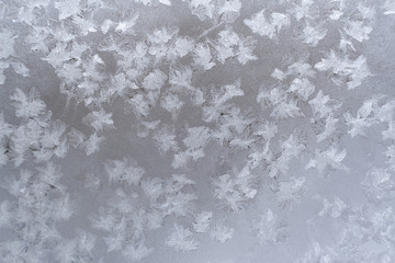 Close-up icy pattern of frozen snowflakes on window pane. 