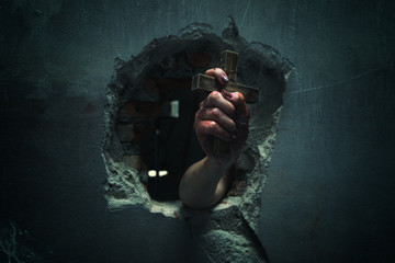 Horror Scene with Bloody Hand is holding a holy cross.