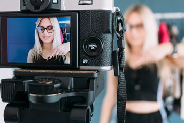 fashion stylist vlogging. social media influencer creating content. video streaming. woman telling to push the subscribe button to her viewers standing in clothing showroom