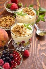Dessert with fresh berries, granola and custard in glasses, vertical