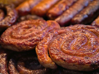 Grilling sausages on barbecue grill. Closeup of sausage on the grill. Selective focus. Cook puts sausage roasted on the grill. Oktoberfest food, appetizing beer snacks set for big company, close up.