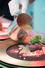 A chef prepares a fried beef gourmet dinner.